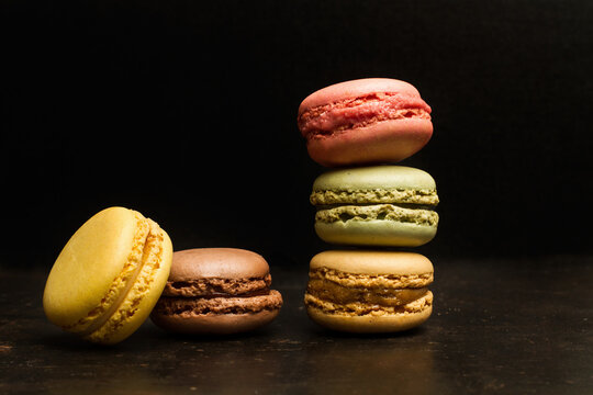 Macarons sabrosos de diferentes sabores sobre un fondo oscuro insaturado liso y aislado. Vista de frente y de cerca. Macro. Copy space