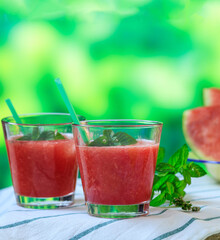 Watermelon juice glasses closeup view, blur green nature background