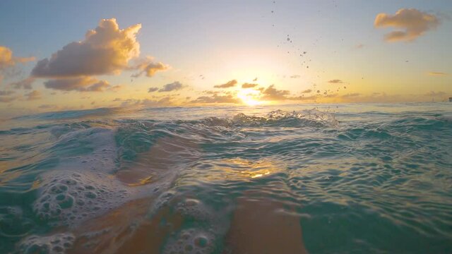 SLOW MOTION, POV: Young woman swimming in the turquoise ocean kicks her feet and watches the picturesque golden sunset. Swimming backstroke in the Caribbean sea and observing the stunning sunset.