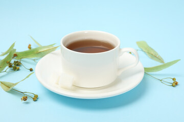 Cup of linden tea on blue background, close up