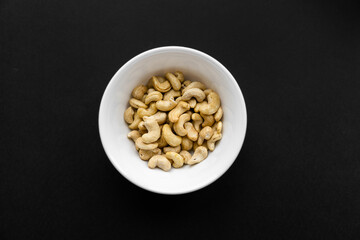 Cashew nuts in a small plate on a black table as a background. Cashew nut is a healthy vegetarian protein nutritious food.