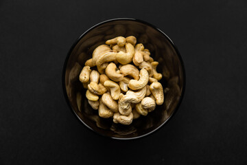 Cashew nuts in a small plate on a black table as a background. Cashew nut is a healthy vegetarian protein nutritious food.