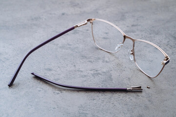 Closeup of corrective eyeglasses with broken temple lying on table in optic. Professional...
