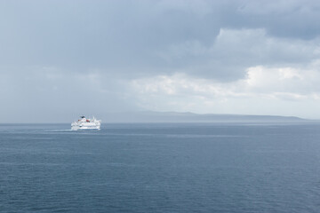Big white Croatian ferry sailing out of Split going to the islands. Alone on the sea on a rainy storm day, dark clouds stretching into the distance