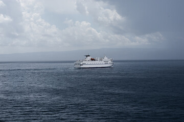Big white Croatian ferry sailing out of Split going to the islands. Alone on the sea on a rainy storm day, dark clouds stretching into the distance