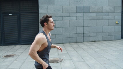 Fototapeta na wymiar Sporty man running outdoor. Male runner jogging on city street in slow motion.