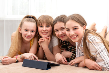 girls teenagers are lying on the sofa and have fun watching something interesting on the tablet.  Happy youth concept