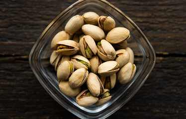 Pistachios in a small plate on a vintage wooden table. Pistachio is a healthy vegetarian protein nutritious food. Natural nuts snacks.