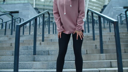 Closeup female legs running down stairs. Tired girl wiping sweat on city street