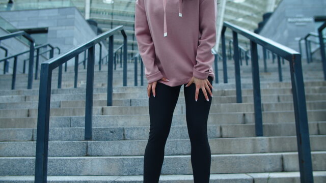 Closeup female legs running down stairs. Tired girl wiping sweat on city street