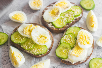 Sandwiches with egg, cucumber, sesame seeds and spices. Tasty breakfast. Sandwiches on the table