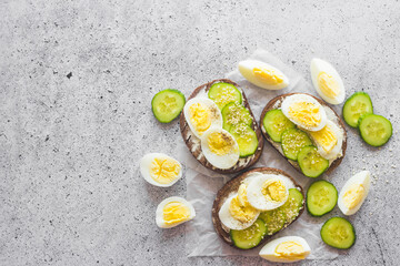 Sandwiches with egg, cucumber, sesame seeds and spices. Tasty breakfast. Sandwiches on the table