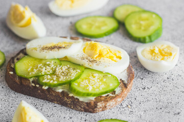 Sandwich with egg, cucumber, sesame seeds and spices. Tasty breakfast. Sandwich on the table