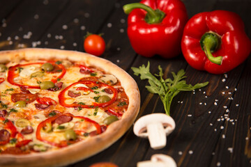 Part of pizza with bell pepper, champignons, cherry tomatoes and herbs on wooden board background. Close up of uncut pizza
