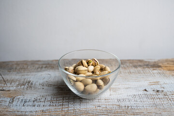 Pistachios in a small plate on a vintage wooden table. Pistachio is a healthy vegetarian protein nutritious food. Natural nuts snacks.