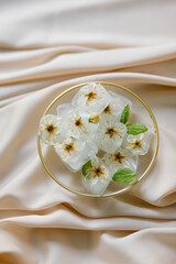 Ice cubes with flowers on silk. Fashion photography.
