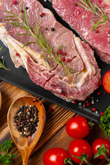 Two raw beef steaks on dark wooden table