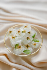 Ice cubes with flowers on silk. Fashion photography.
