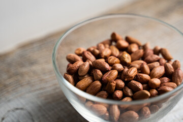 Peanut nuts in a small plate on a vintage wooden table. Peanuts nut is a healthy vegetarian protein nutritious food.