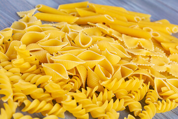 Different dry pasta on a wooden background