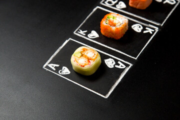 Hand drawn Poker cards with Japanese sushi roll pieces on dark chalkboard background. Asian roll without rice with cucumber and crunchy shrimp. Queen, King and Ace of Hearts chalk cards
