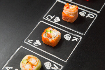 hand drawn Poker cards with Japanese sushi roll pieces on dark chalkboard background. Asian rolls with crunchy shrimp, cucumber, salmon and flying fish roe. Queen, King and Ace of Hearts chalk cards
