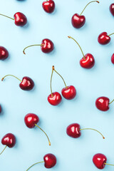 Obraz na płótnie Canvas Bright pattern of ripe cherries on a blue background. Flat lay, top view.