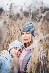 Fototapeta premium Teen girl and mom walking in the winter forest, plants, snow and cold, frosty air