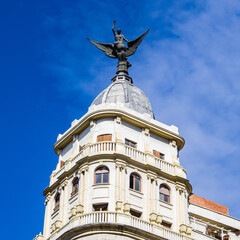 Fototapeta na wymiar It's Statue of Angel on the Hotel on the Gran Via street (Great Way), Madrid, Spain. Gran via is known as the the street that never sleeps or as Spanish Brodway