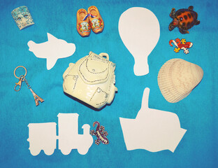 Flat lay of souvenirs, seashell and paper figures against blue background, concept for travelling ,...