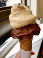 Hand holding an Ice cream cone with Chocolate and Vanilla scoops. No people.