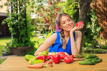 Young pretty smiling girl with organic fresh vegetables is sitting at the table, photography for blog and advertising