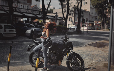 Fototapeta na wymiar Young attractive girl with the motorbike enjoys the sun
