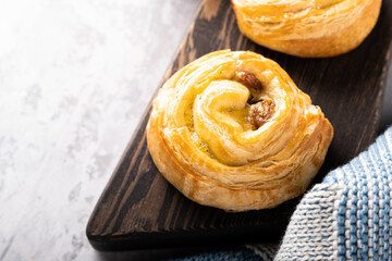 Fresh pastry sweet swirl buns with raisins on wooden board for breakfast or brunch. Party food concept.