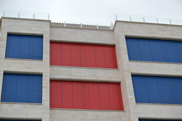 Closed, red and blue blinds of vacation apartments at the coast on the costa blanca in Spain during the corona-time.