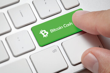 Macro of male hand pressing computer key with bitcoin cash currency symbol and text.cryptocurrency and fast internet concept.