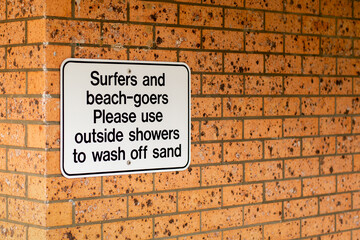 Notice on a brick wall - Surfers and beach-goers please use outside showers to wash off sand.