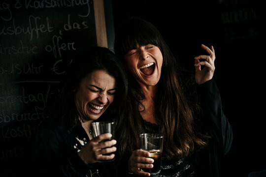 Europe, Germany, Berlin, Woman having fun whilst drinking in a bar.