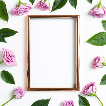 Empty photo frame with pink rose flowers on white background. Floral composition, flat lay, top view, copy space