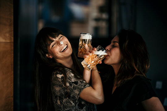 Europe, Germany, Berlin, Woman having fun whilst drinking beer in a bar.