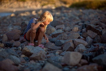 little girl plays on stones, she is looking for a lost toy