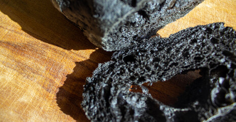 Black bread on a plank and black table. Above view of healthy bread. Strange food. Halloween bread...