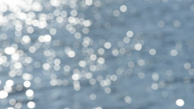Bokeh sun glare reflected in water surface. Sunrays flickering in water stream. 