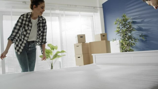 Tracking video of happy couple putting mattress on the bed. Shot with RED helium camera in 8K