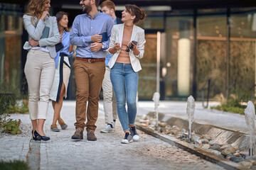 cropped image of colleagues  walking, talking and laughing in front of business building