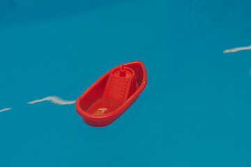 red plastic toy ship on the water in the pool