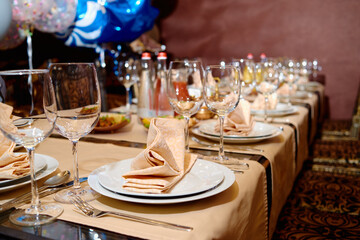 Table setting with sparkling wineglasses, plates with napkins and cutlery on table, copy space. Place set at wedding reception. Table served for wedding banquet in restaurant