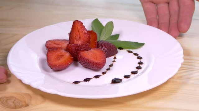 Strawberries on a silver platter. Dessert dish made from slices of strawberries and sprigs of mint. Serving dessert in a restaurant.