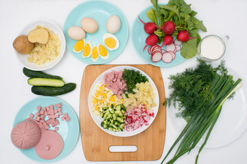step by step recipe for Russian cold okroshka soup, ingredients for homemade okroshka-sausage, greens, eggs, cucumbers, potatoes, radishes. top view on a light background