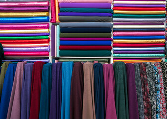 Colorful fabrics. Traditional fabric store with stacks of colorful textiles at market stall. Front side in focus, back side out of focus. Many color fabric rolls in the fabric shop.